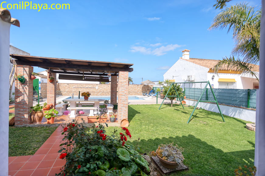 Jardín amplio con merendero de ladrillo, columpio y césped junto a vivienda