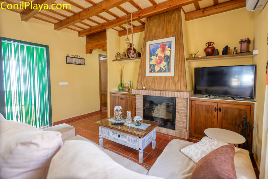 Salón acogedor con chimenea, sofá claro y muebles de madera rústica