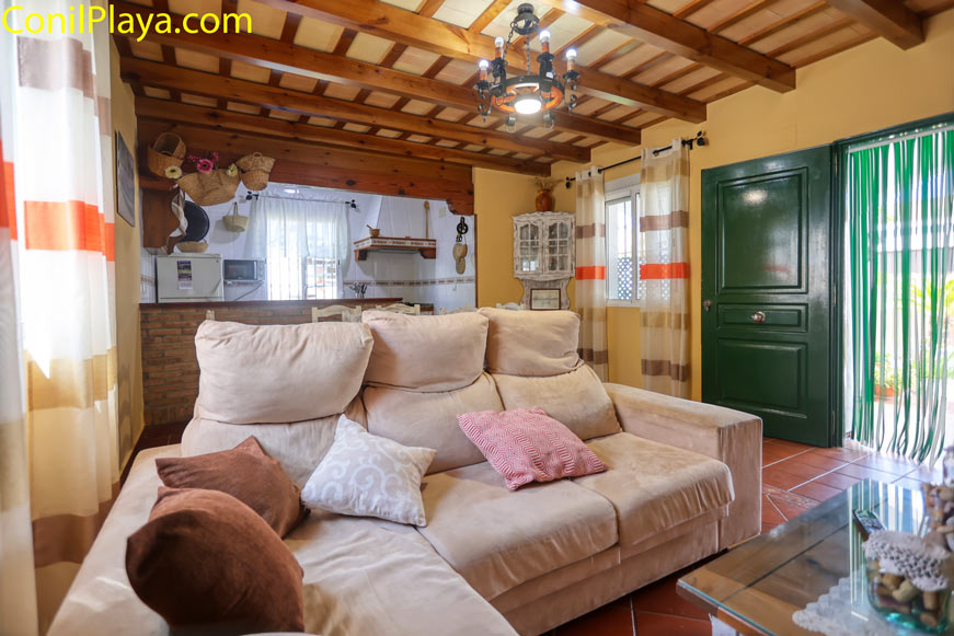 Salón acogedor con sofá grande, cortinas claras y detalles rústicos visibles