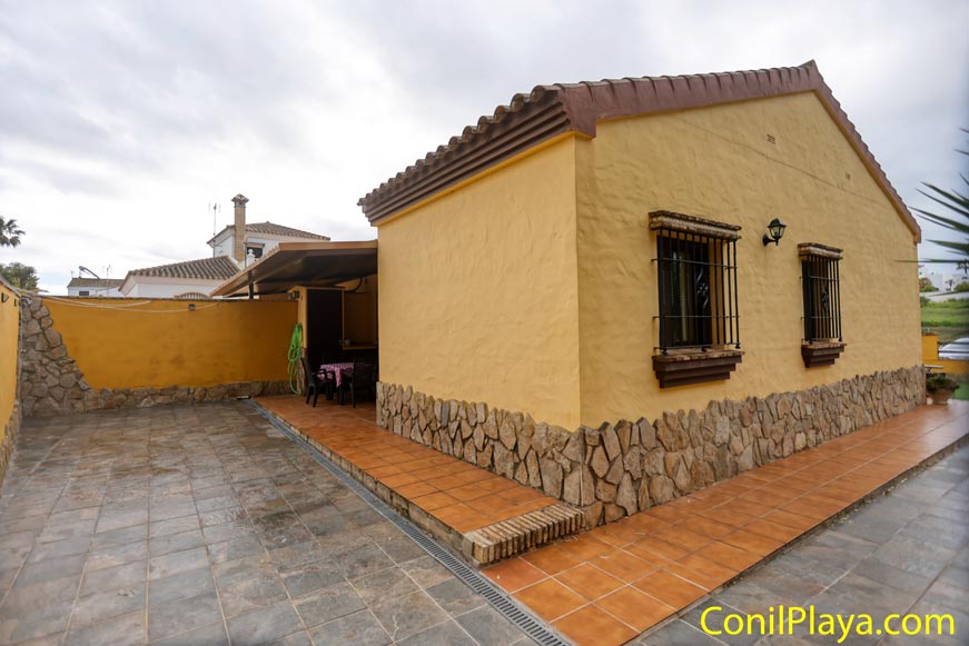 Casa rural de una planta con paredes amarillas, patio grande y ventanas con rejas.