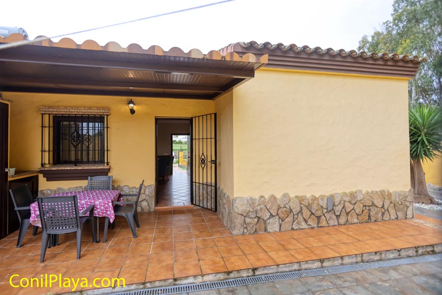 Patio trasero con mesa y sillas de exterior bajo porche.