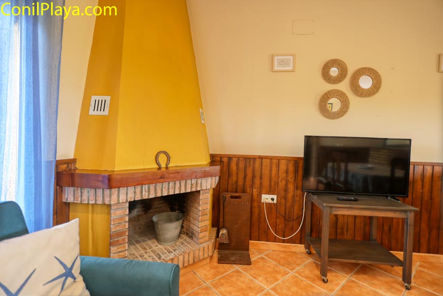 Salón con chimenea de ladrillo, televisor y decoración en pared