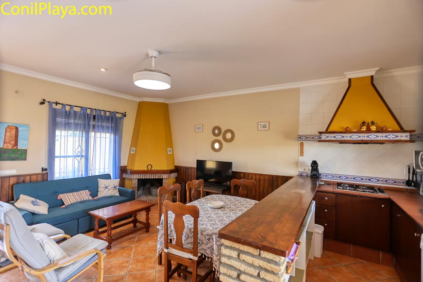 Salón con chimenea y cocina americana en chalet en alquiler en Conil