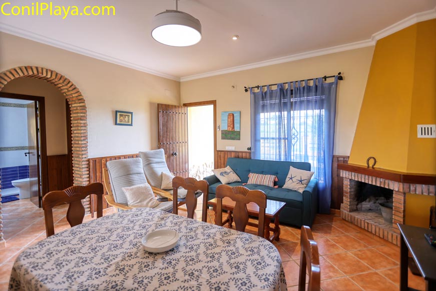 Salón acogedor con chimenea, sofá azul y mesa de comedor para cuatro personas