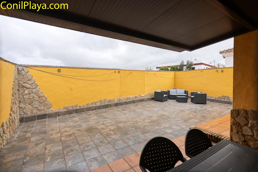 Amplia terraza exterior con muebles de jardín y pared amarilla de piedra