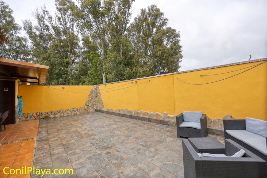 Terraza exterior con pared amarilla y muebles de jardín modernos