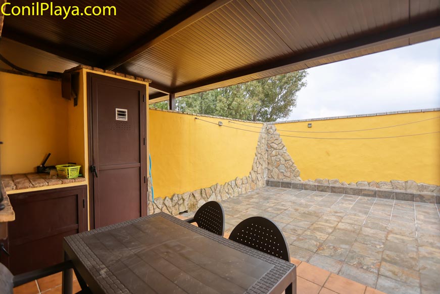Porche exterior cubierto con mesa y sillas y patio de suelo de piedra