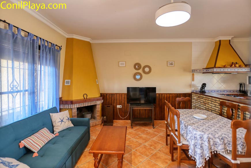 Salón acogedor con sofá azul, chimenea y comedor junto a la cocina