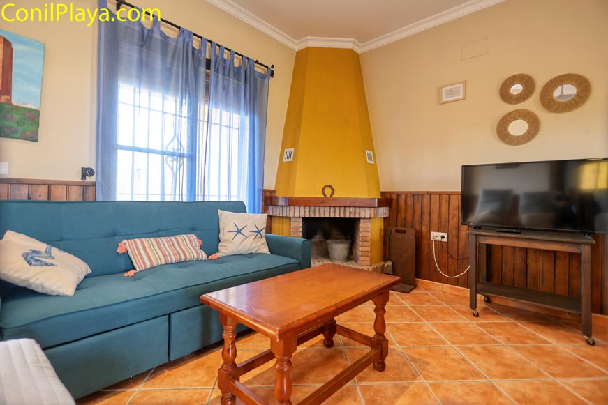 Salón con sofá azul, chimenea amarilla y televisión moderna en esquina