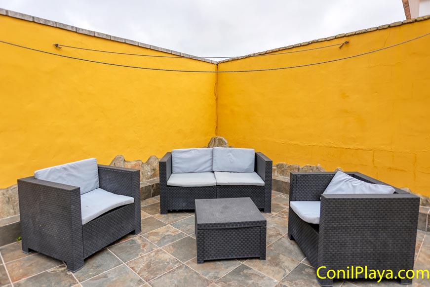 Terraza con muebles de exterior y pared amarilla decorativa