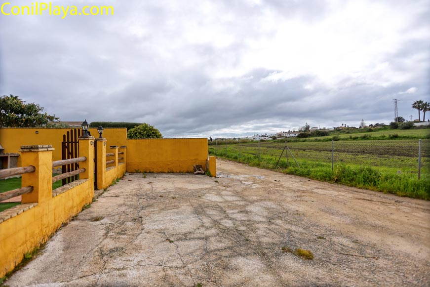 Aparcamiento exterior junto a muro amarillo y zona rural abierta