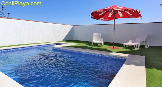 piscina con 2 tumbonas y sombrilla