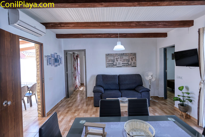 Salón moderno con sofá azul, aire acondicionado y techo con vigas de madera