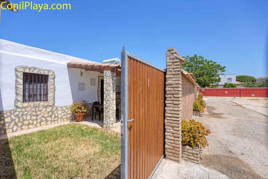 Entrada al porche de una casa con pared de piedra y pequeño jardín