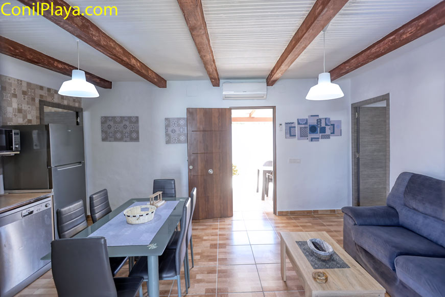 Salón con sofá, mesa de comedor y cocina integrada visible