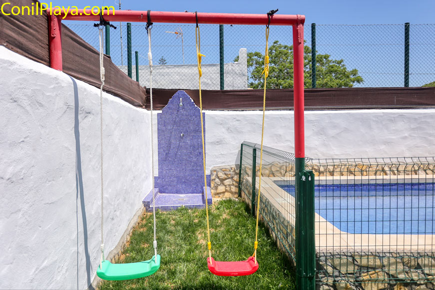 Zona exterior con columpios infantiles junto a la piscina privada vallada