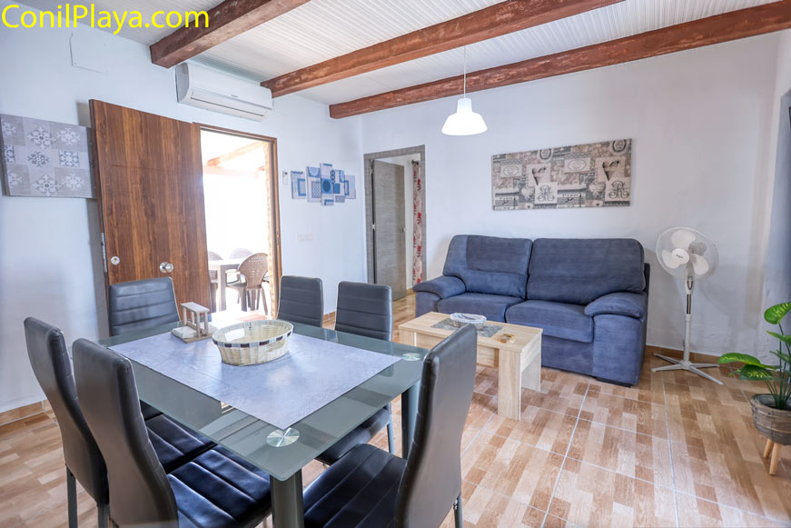 Salón con sofá azul, mesa comedor y aire acondicionado visible