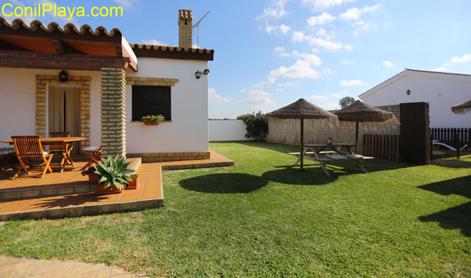 El chalet en Conil tiene una mesa con sombrillas en el jardín