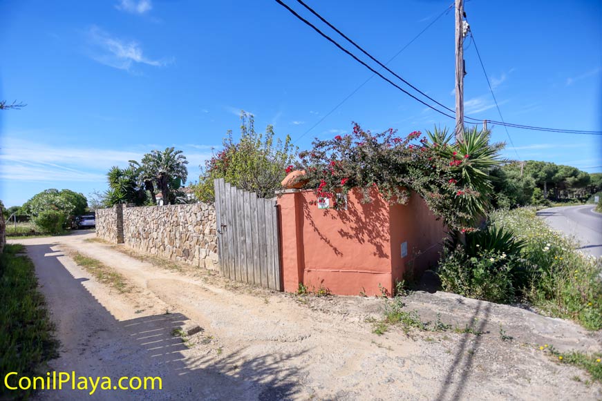 Entrada de casa con muro de piedra y portón de madera vista desde el camino