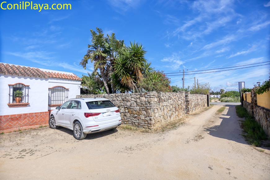 Aparcamiento con coche junto a la casa y muro de piedra