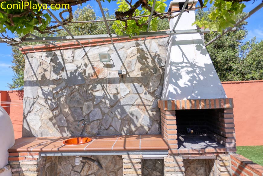 Barbacoa de obra y fregadero en jardín con sombra de parra