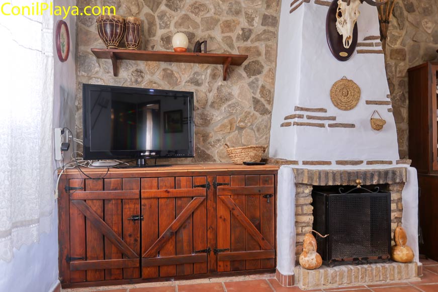 Chimenea de obra junto a mueble de madera y televisión en el salón
