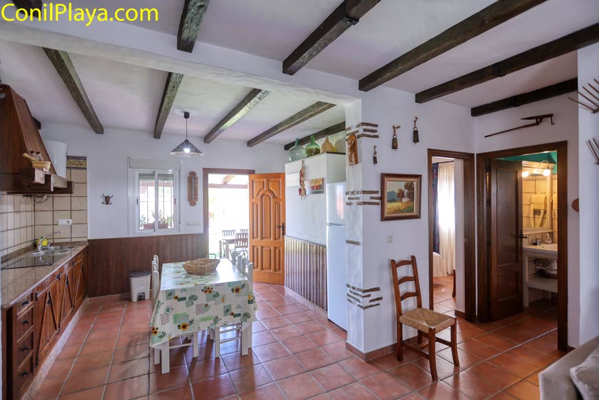 Cocina rústica luminosa con mesa comedor y vista a baño y dormitorio