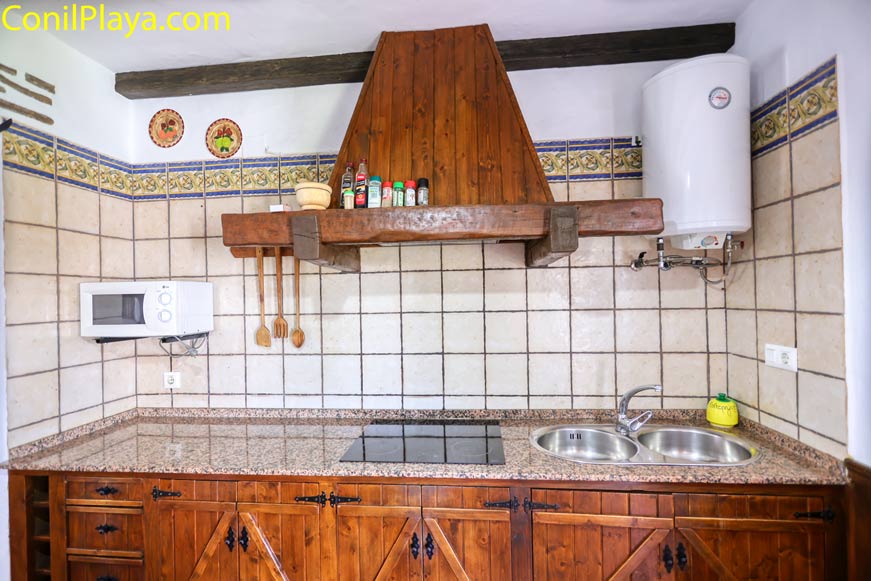 Cocina rústica con encimera de granito y campana de madera vista frontal