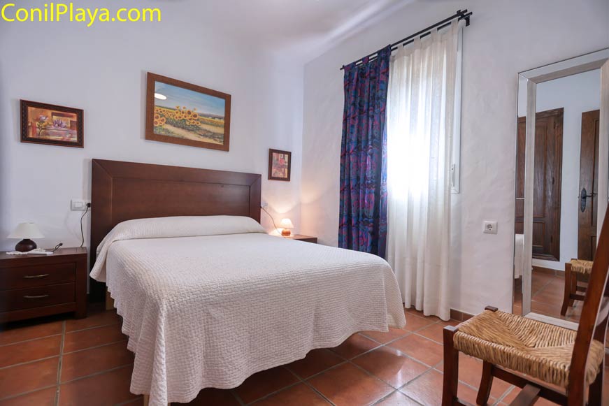 Dormitorio con cama de matrimonio, muebles de madera y ventana luminosa