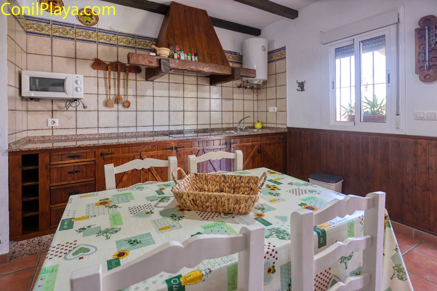 Cocina rústica vista desde la mesa, con muebles de madera y ventana lateral