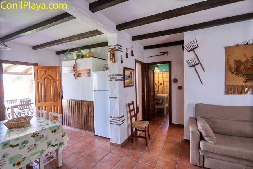 Salón rústico con sofá y comedor junto a entrada y acceso al pasillo