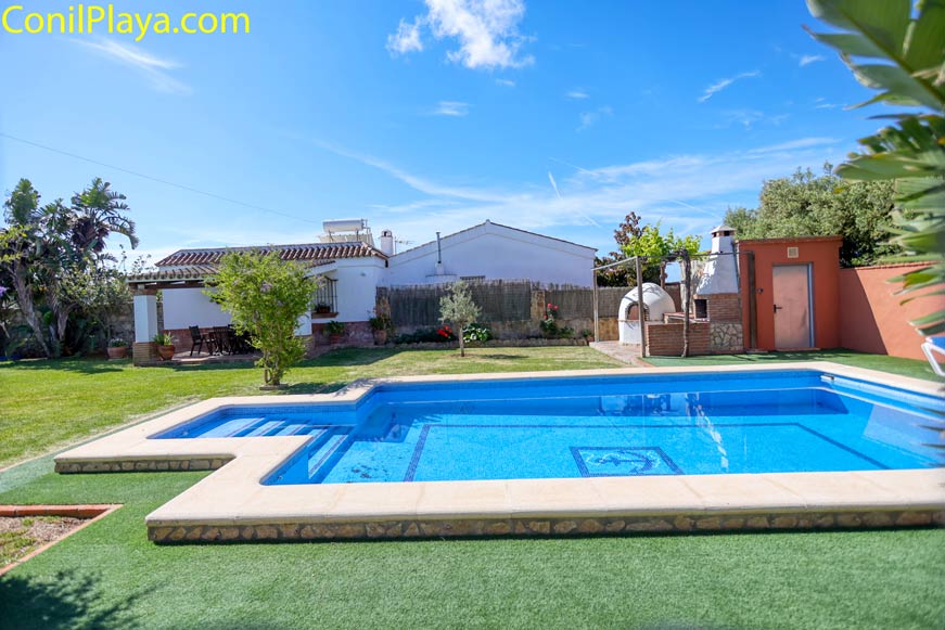 Piscina privada en jardín con césped y zona de barbacoa junto a vivienda