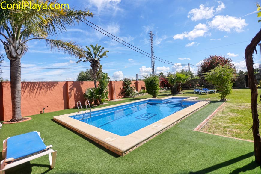Piscina rectangular rodeada de jardín y zona de césped, vista lateral
