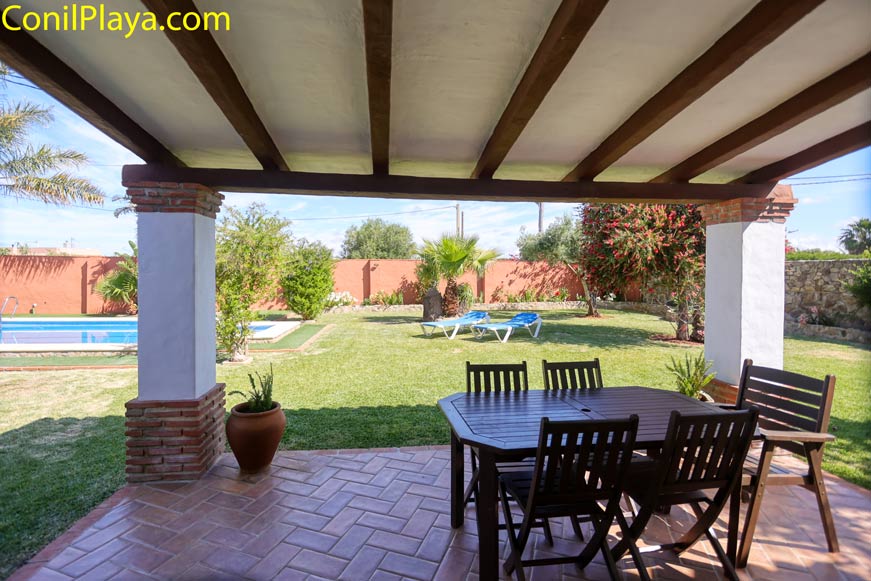 Porche cubierto con mesa y sillas vistas a jardín y piscina privada
