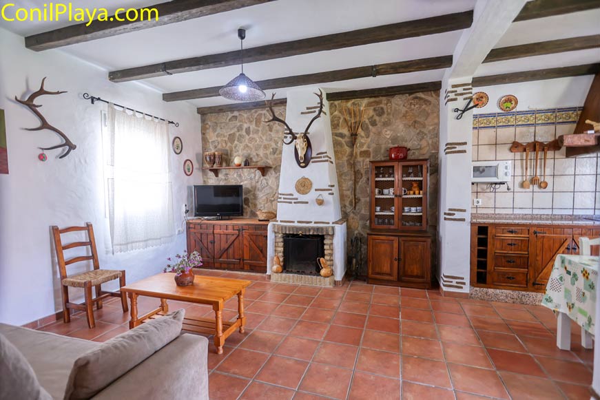 Salón rústico con chimenea y decoración en madera junto a cocina abierta