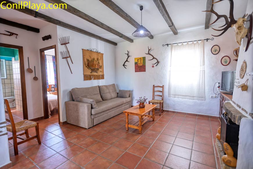 Salón rústico con sofá beige, chimenea y decoración tradicional vista amplia