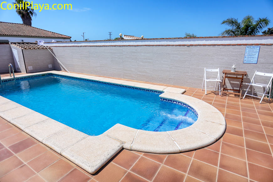 Piscina privada exterior Piscina privada con suelo de baldosas y zona de sillas plegables