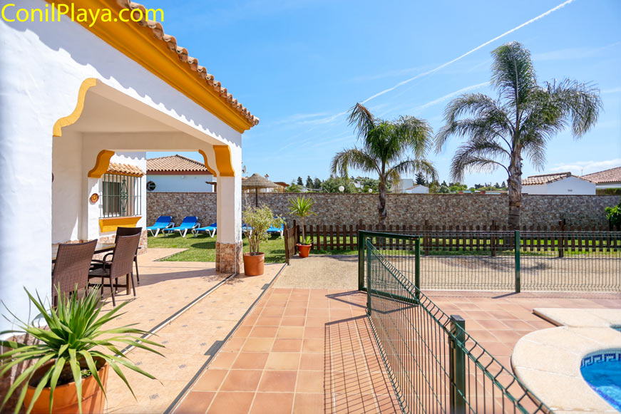 Porche con jardín y piscina Porche con mesa, sillas y jardín con palmeras y piscina visible