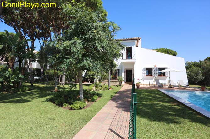 jardín con césped y la piscina al fondo