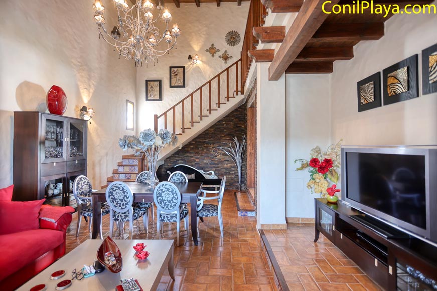 Comedor elegante con mesa y sillas cerca de escaleras y televisor