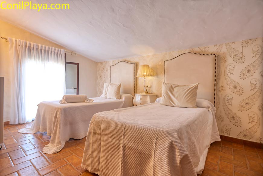 Dormitorio con dos camas individuales decoración cálida y luz natural