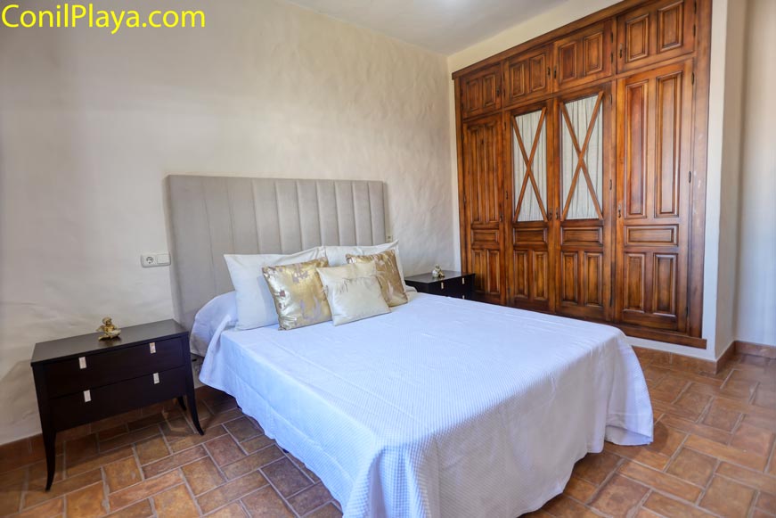 Dormitorio con cama de matrimonio y gran armario de madera visto desde la entrada