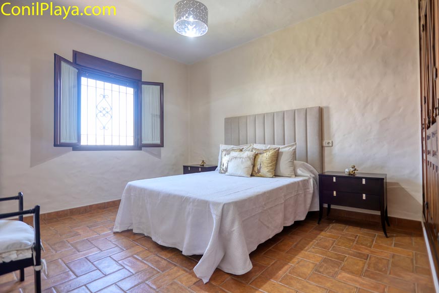 Dormitorio con cama de matrimonio y ventana abierta al fondo