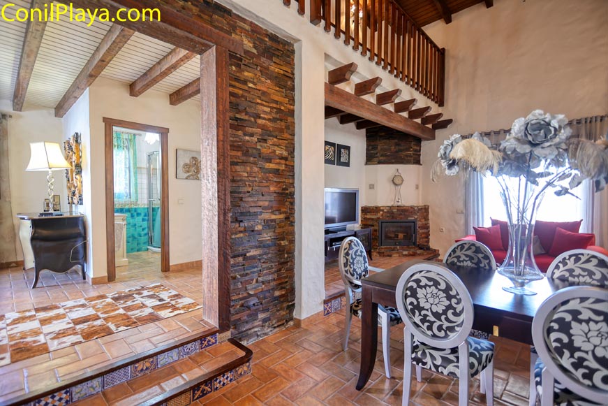 Salón rústico con comedor y chimenea visto desde la entrada principal