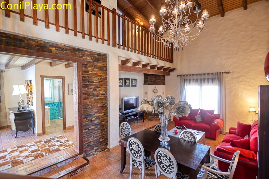 Salón rústico con sofá rojo comedor y lámpara techo vistas abiertas