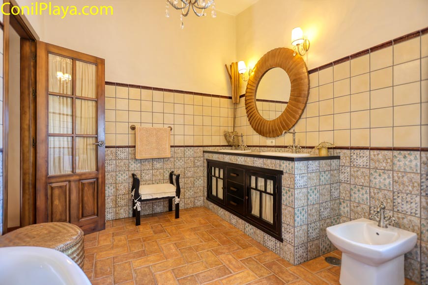 Cuarto de baño amplio con lavabo doble y suelo de baldosas visto desde la puerta