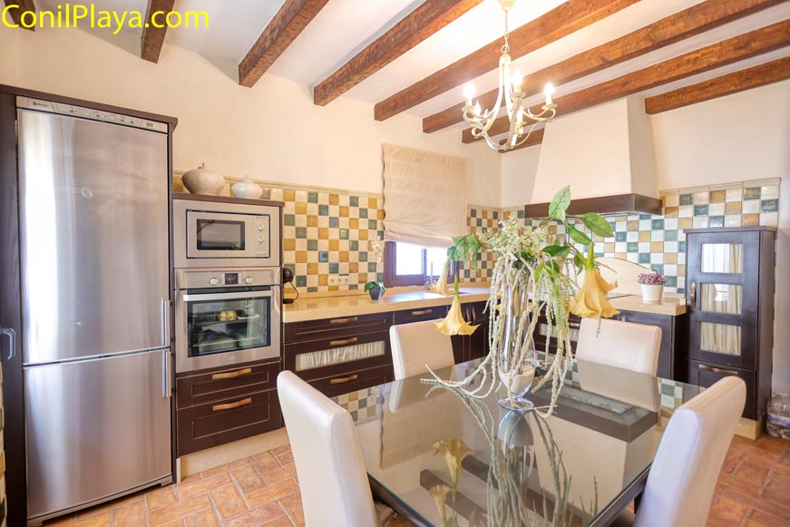 Cocina rústica con mesa de cristal y electrodomésticos modernos al fondo