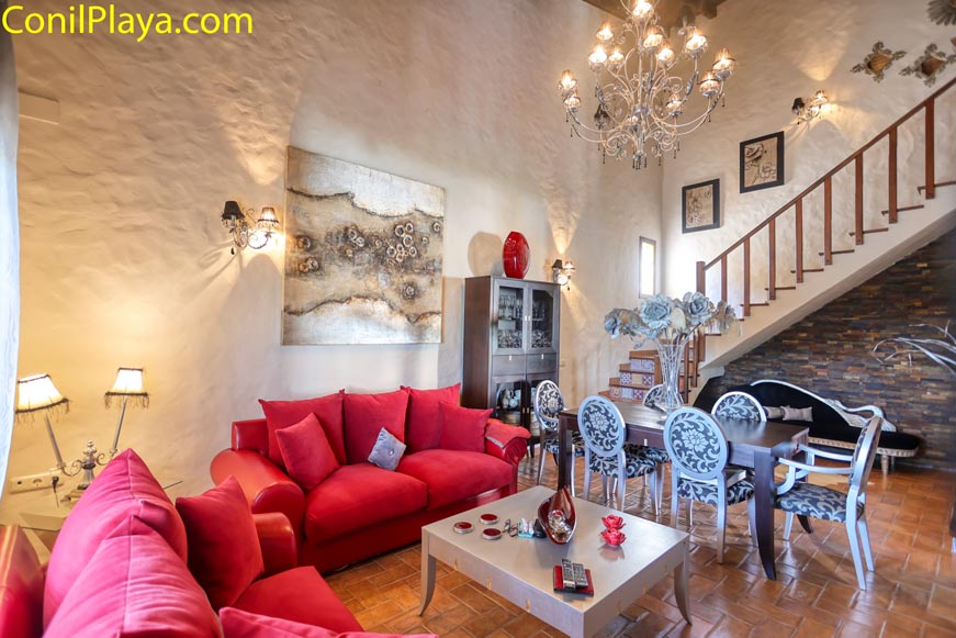 Salón amplio con sofá rojo, mesa comedor y escalera decorativa