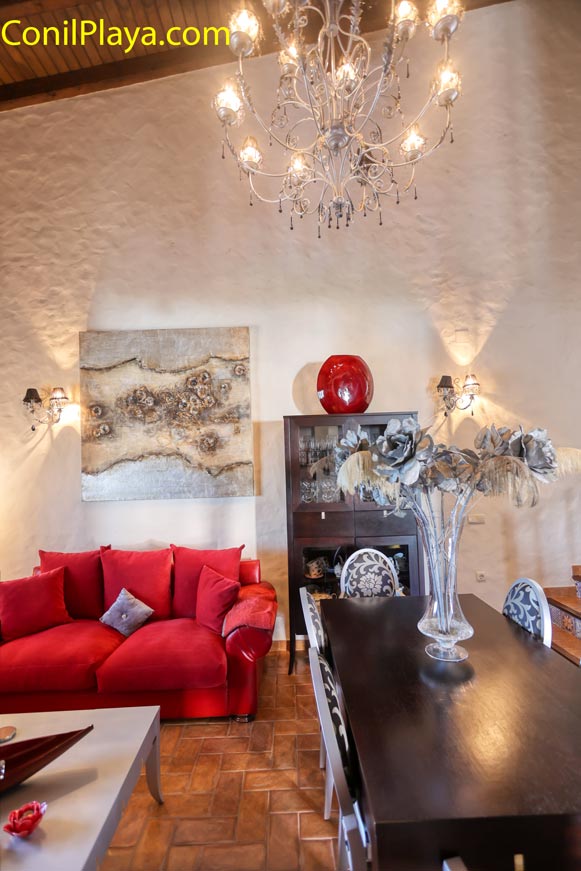 Salón con sofá rojo mesa comedor lámpara y decoración elegante desde el acceso principal
