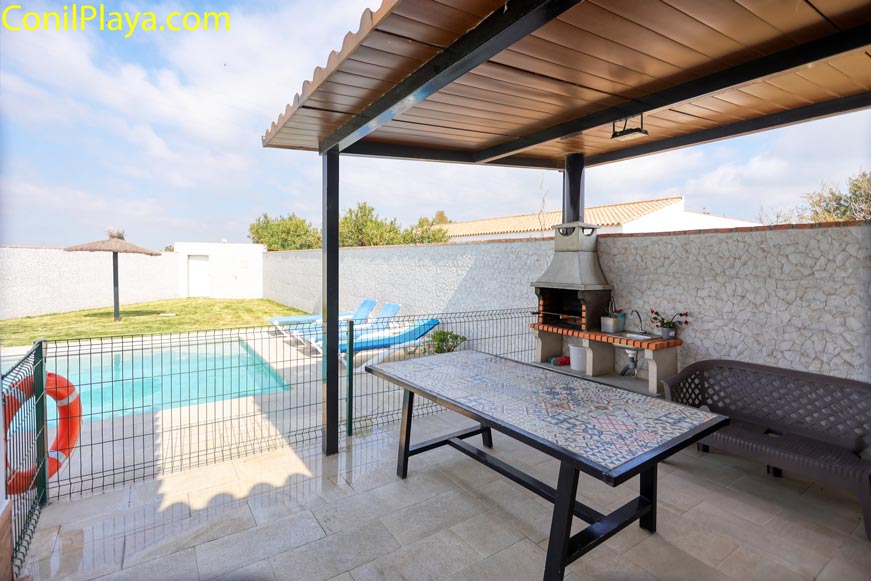 Comedor exterior con barbacoa y vistas al área de piscina